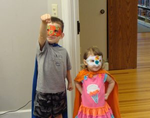 Little boy and girl dressed like superheros with masks and capes.