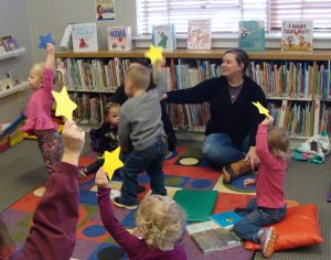 Children and parents holding yellow paper stars in the air.